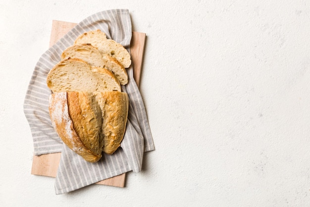 Freshly baked bread slices on cutting board against white wooden background top view Sliced bread