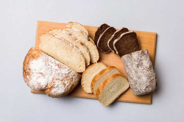 Freshly baked bread slices on cutting board against white wooden background top view Sliced bread