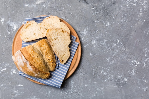 Freshly baked bread slices on cutting board against white wooden background top view Sliced bread