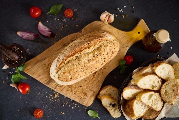 Freshly baked bread on wooden cutting board on dark table