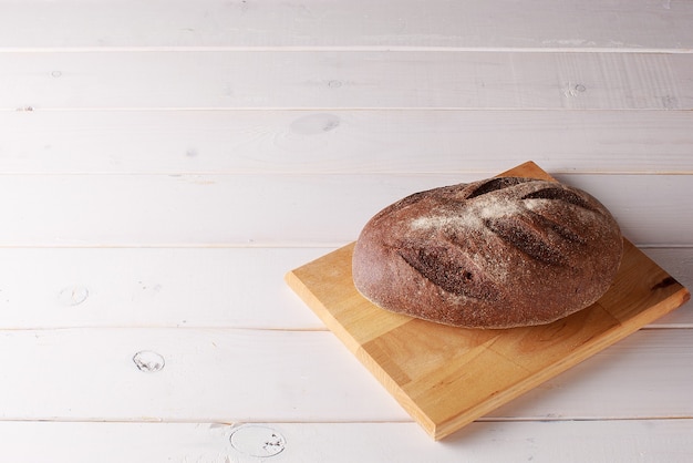 Freshly baked bread on wooden desk on white wooden kitchen table