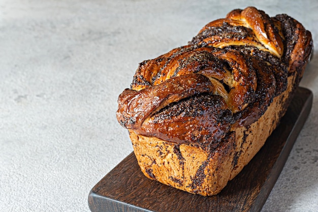 Freshly baked briocheBabka with poppy seeds and chocolate on a wooden board. Braided dessert bread.