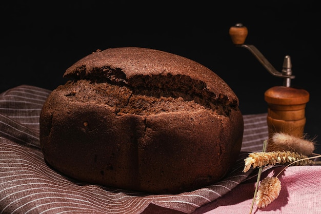 Freshly baked brown rye bread on wooden cutting board on black background