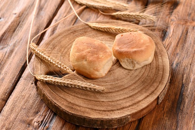 Freshly baked buns and ears of wheat on a wooden table