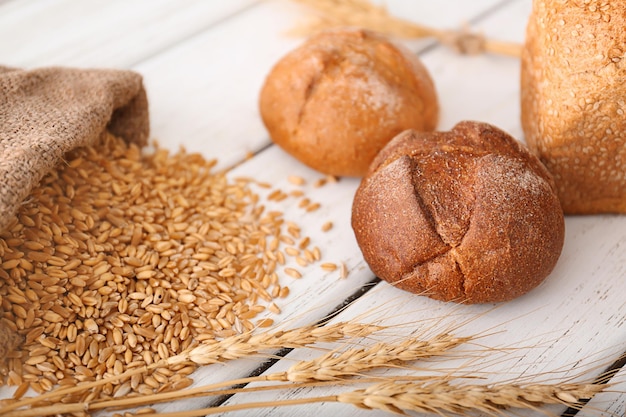 Freshly baked buns wheat grains and spikes on table Homemade bread