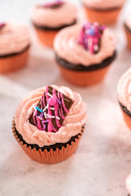 Freshly baked chocolate strawberry cupcakes garnished with gourmet mini pink chocolates