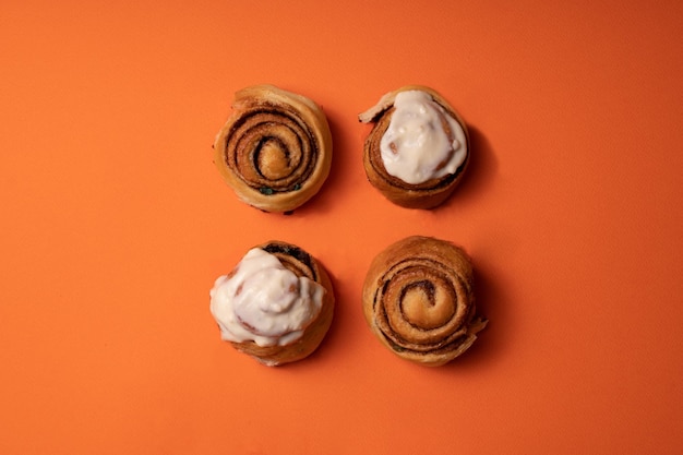 Freshly baked cinnamon buns on an orange background top view. patern. copy space