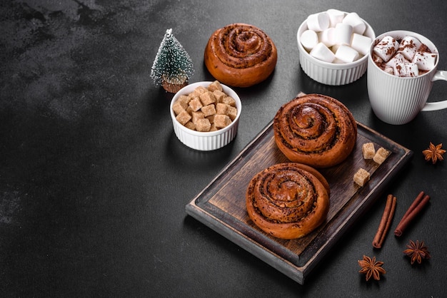 Freshly baked cinnamon roll with spices and cocoa filling on a black background. Cinnabon buns. Swedish breakfast.