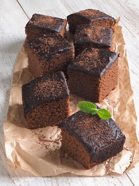 Photo freshly baked classic brownie on parchment are laid out on a whi