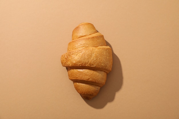 Freshly baked croissant on craft background, top view