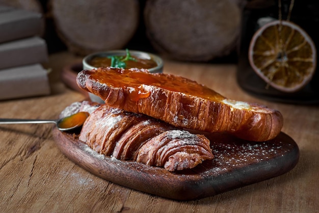 Freshly Baked Croissant with Apricot Jam and Table a spoon close up on Rustic Wooden background