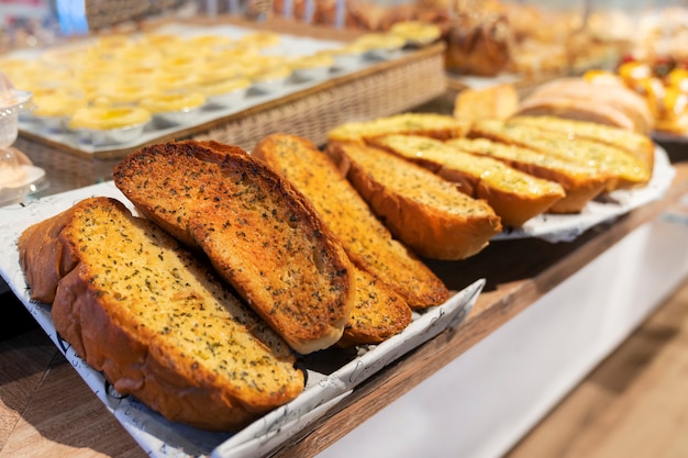 Freshly baked delicious garlic bread with herbs, sliced, on the window counter of a bakery store, close-up photo