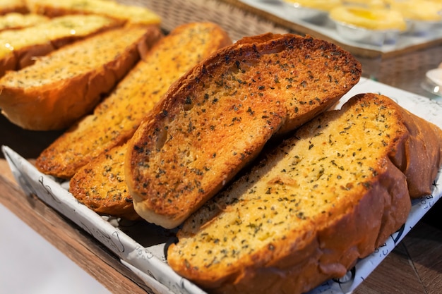 Freshly baked delicious garlic bread with herbs, sliced, on the window counter of a bakery store, close-up photo