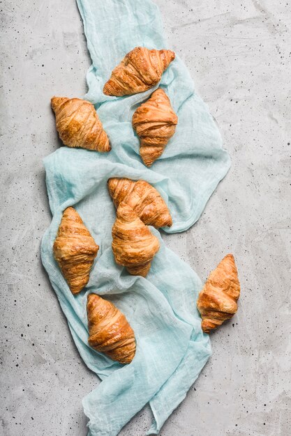 Photo freshly baked french croissants on a turquoise napkin on a light grey surface