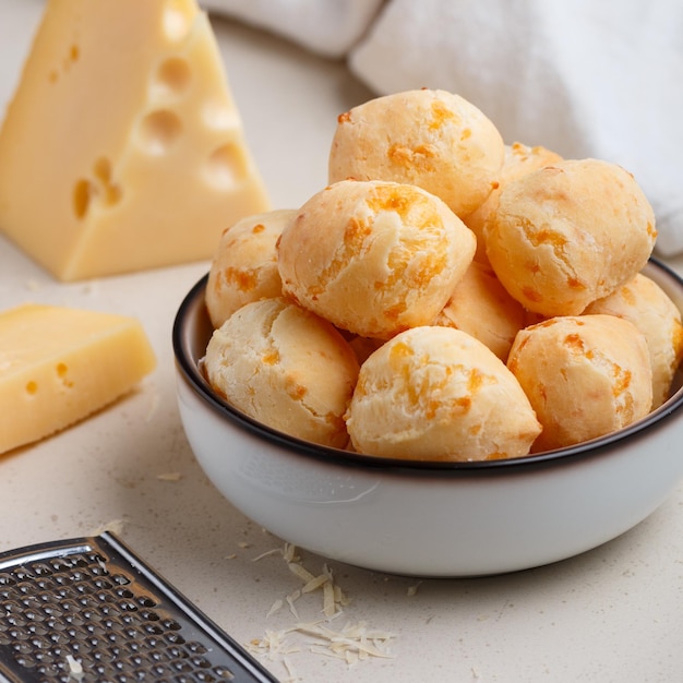 Freshly baked homemade cheese buns in a white plate on a light background closeup A gourmet snack Delicious pastries Selective focus square picture