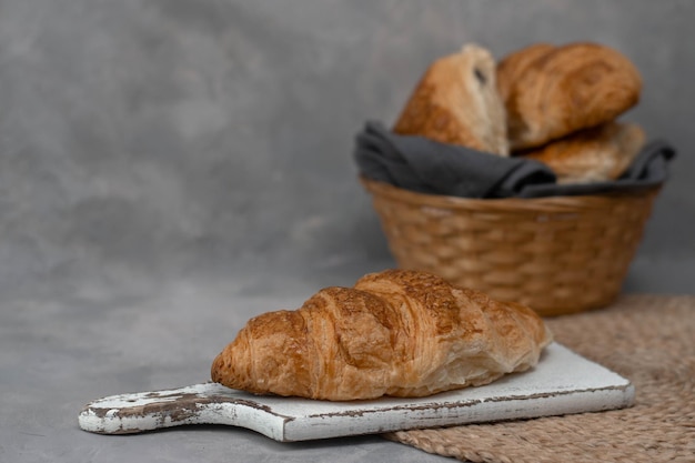 Freshly baked homemade croissants for breakfast. Traditional and whole-grain croissant in a gray plate on a concrete or stone background.