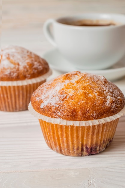 Freshly baked homemade muffins with sugar powder and a cup of coffee