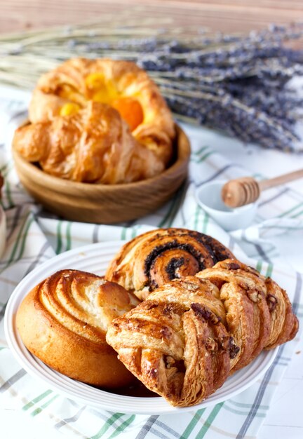 Freshly baked homemade sweet buns with poppy seeds and honey on table in saucer