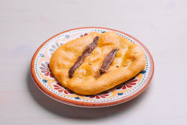 Freshly baked mini pizza with anchovy and oil. Traditional Spanish pastry with vegetables.