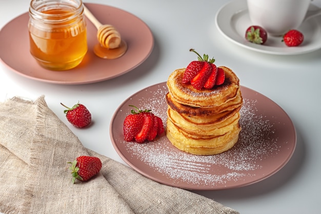 Freshly baked pancakes with strawberries on a natural wood background