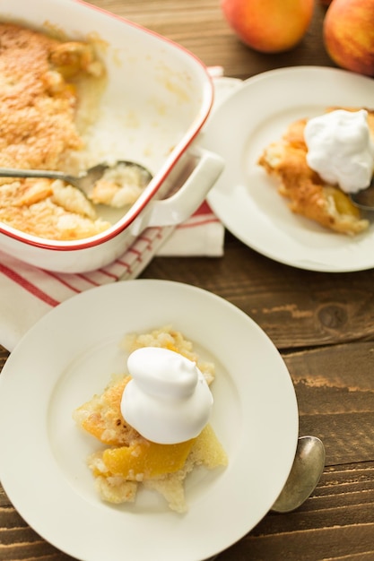 Freshly baked peach cobbler with scoop of whipped cream.