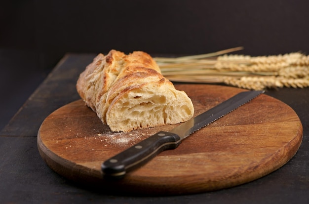 Freshly baked rye bread on a wooden board Fresh bread on table closeup Fresh bread on the kitchen table Whole grain bread put on kitchen wood plate with a knife for cut