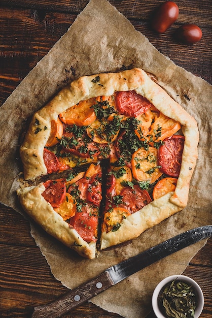 Freshly baked and sliced tomato galette on baking paper View from above