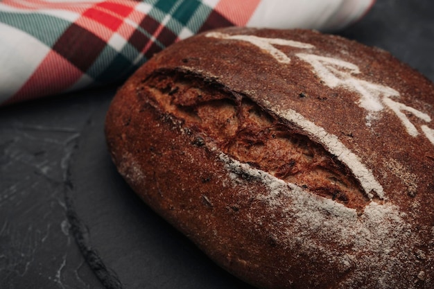 Freshly baked warm delicious rye round bread closeup and a kitchen checkered towel