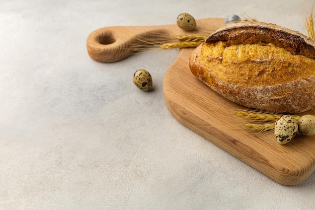 Freshly baked wheat loaf bread on a wooden board on a light background