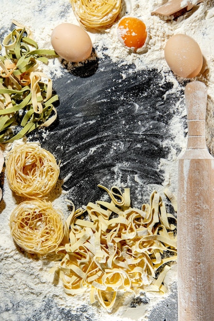 Freshly cooked pasta is lying on a dark surface dusted with flour Italian pasta Tagliatelle Raw pasta Italian pasta recipe Top view copy space