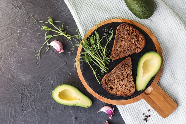 Freshly cooked whole grain toasts with avocado and microgreen sprouts