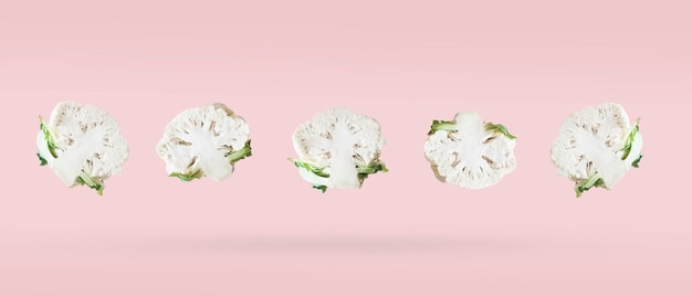 Freshly cut in half cauliflower five pieces soaring on a pink background