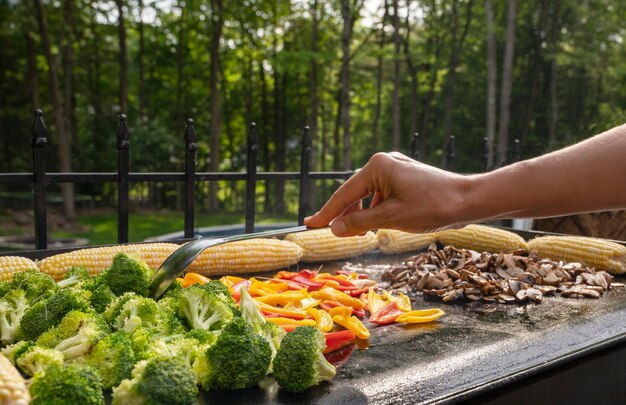 Freshly grilled barbecue corn mushrooms paper and broccoli Person grilling healthy vegetables