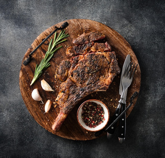 Freshly grilled Tomahawk steak on a wooden cutting board BBQ food top view grey background