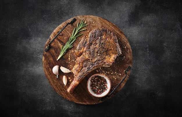 Freshly grilled Tomahawk steak on a wooden cutting board BBQ food top view grey background