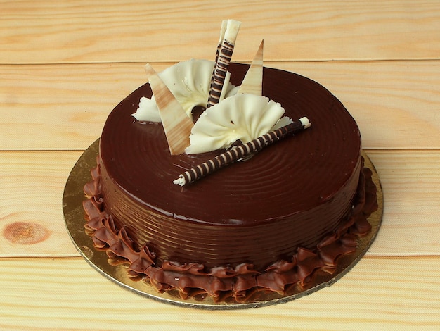 Freshly made chocolate truffle cream cake on wooden table selective focus