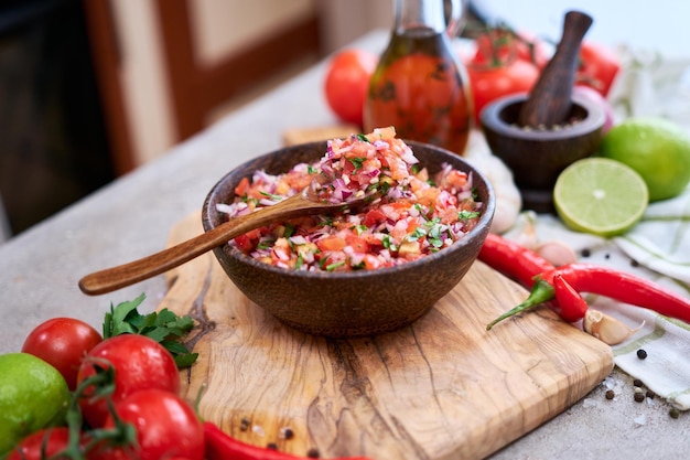 Freshly made salsa dip sauce chopped garlic tomatoes and onion in wooden bowl