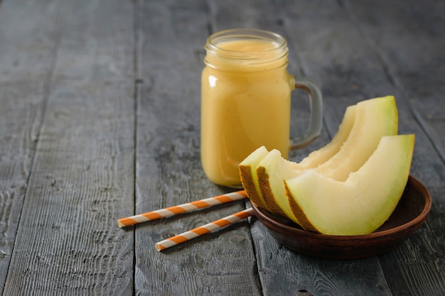 Freshly melon, orange and banana smoothie and three slices of melon on a table