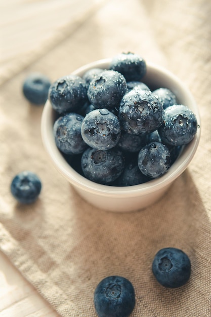 Freshly picked juicy blueberries in the bowl on wooden background close up Blueberries background