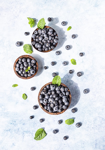 Freshly picked juicy blueberries in wooden bowl with mint. Antioxidant. Concept for healthy eating and nutrition.