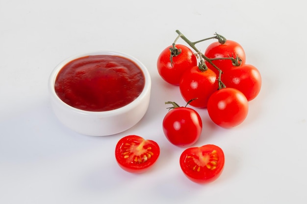 Freshly prepared ketchup with ripe red tomatoes on a white background