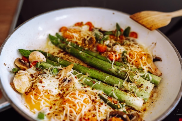 Fried asparagus with cheese and egg in a frying pan