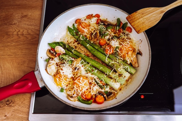 Fried asparagus with cheese and egg in a frying pan