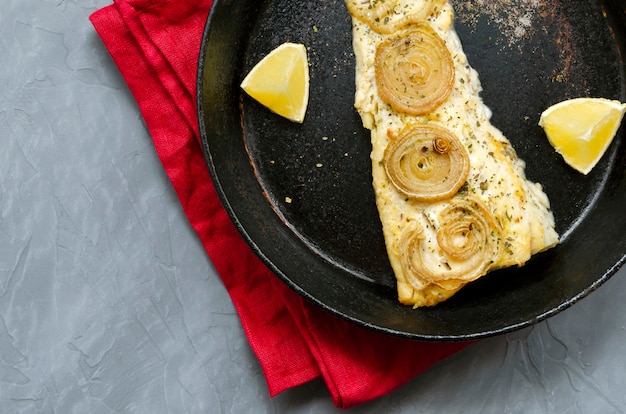 Fried baked mackerel trachurus with onions and dried herbs in an old frying pan