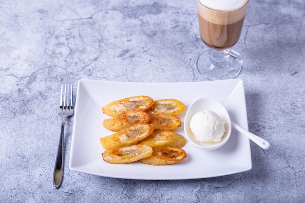 Fried bananas with honey cinnamon coffee and ice cream Closeup