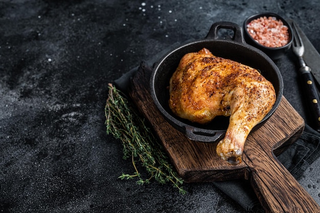 Fried bbq chicken leg in a pan. Black background. Top view. Copy space.