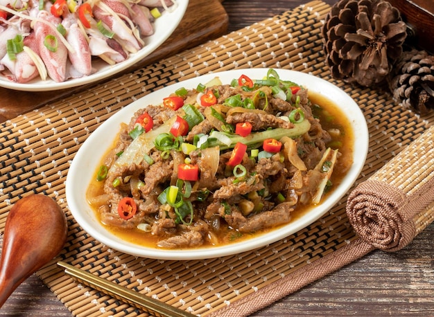 Fried beef with red chilli in a dish isolated on mat side view on dark wooden table taiwan food