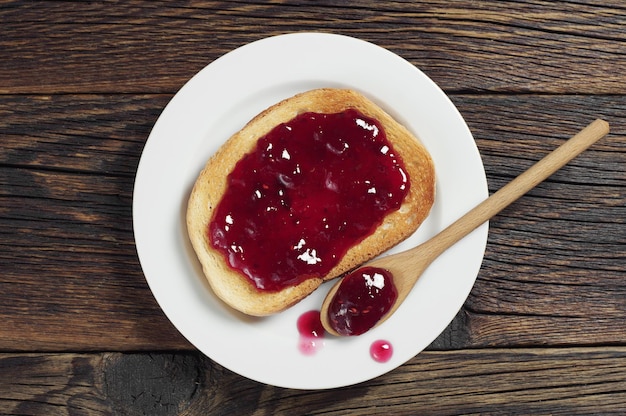 Fried bread with jam on old wooden table, top view