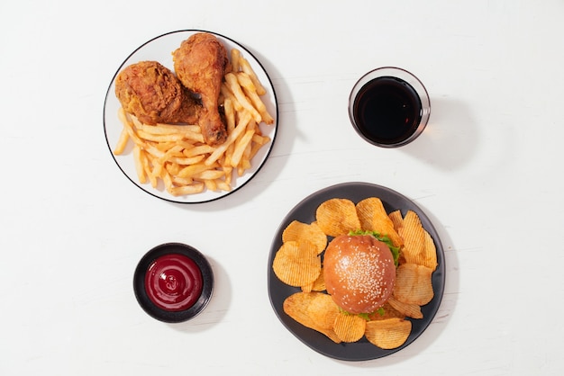 Fried breaded crispy chicken nuggets with French fries on wooden plate, ketchup and soft drink on the side