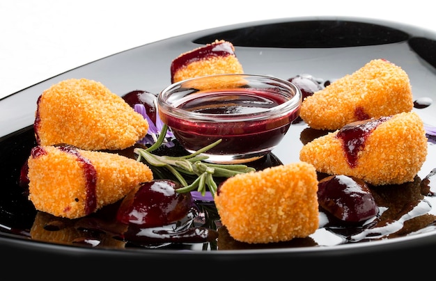 Fried Camembert with cranberry sauce on a glossy black plate